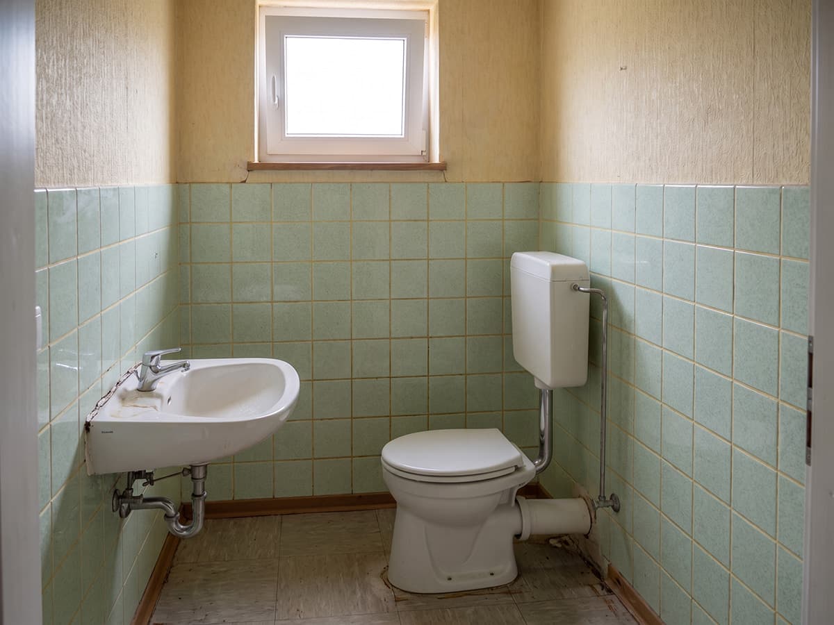 Altes Gäste-WC mit Stand-WC und grünen Fliesen, KI-generiertes Beispielbild