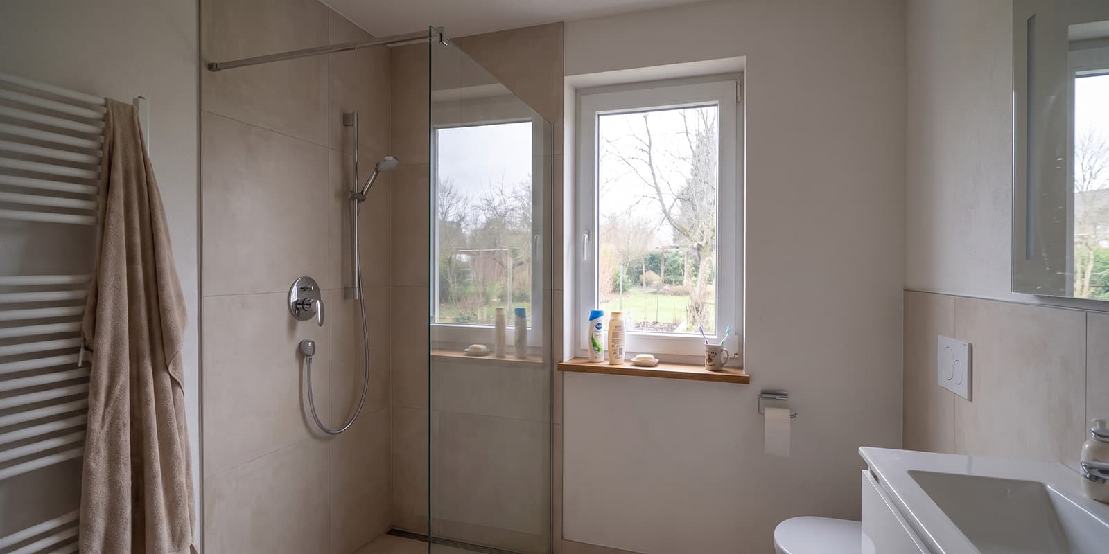 Fertig saniertes Badezimmer mit bodengleicher Dusche, Glasabtrennung und Fenster, KI-generiertes Beispielbild